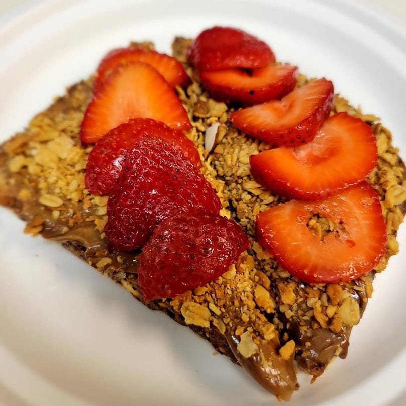A Grouchy John's Coffee crepe topped with chocolate spread, granola, and fresh strawberries.
